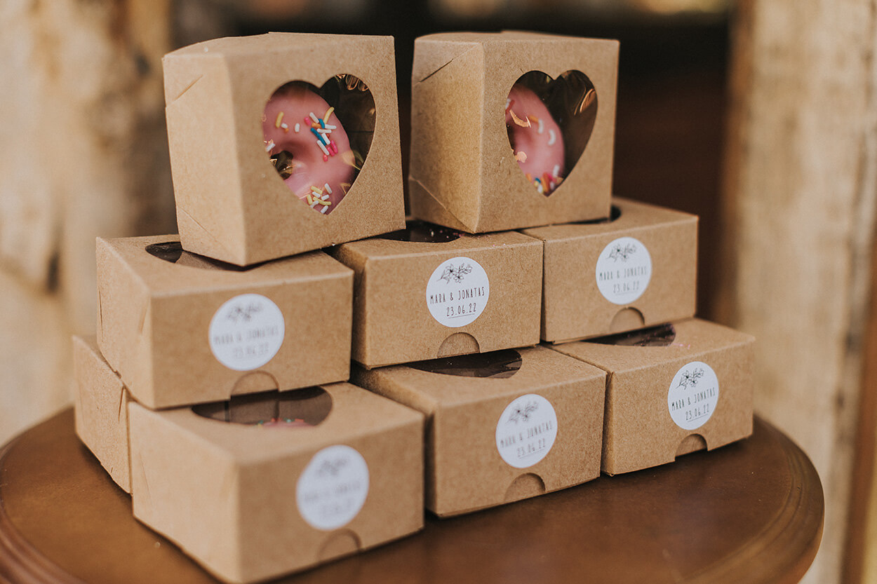 Caixinhas de papelão com coração vazado com donut confeitado como lembrancinha