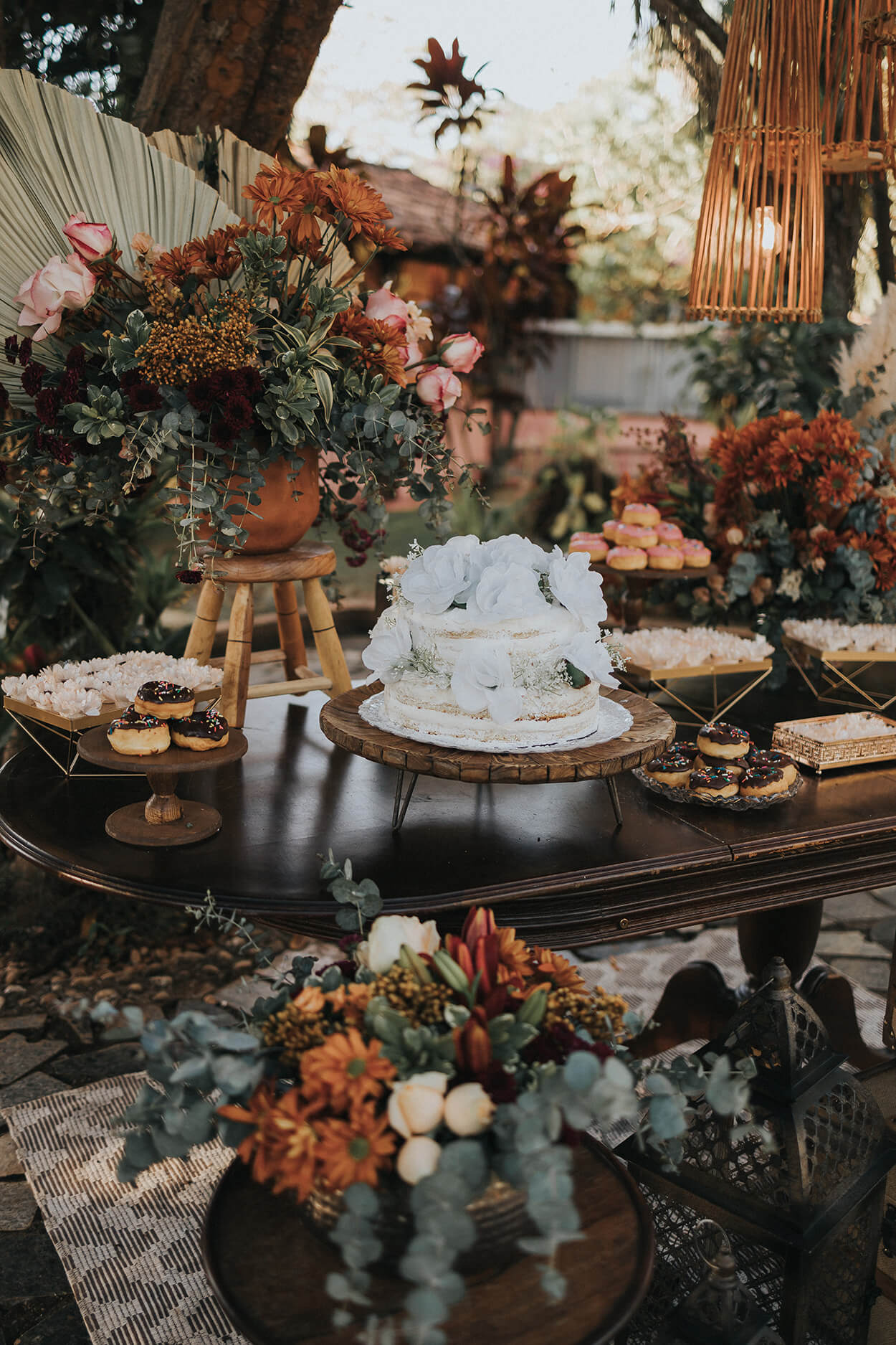 Mesa com bolo de casamento semi espatulado branco com rosas brancas e bandejas com doces