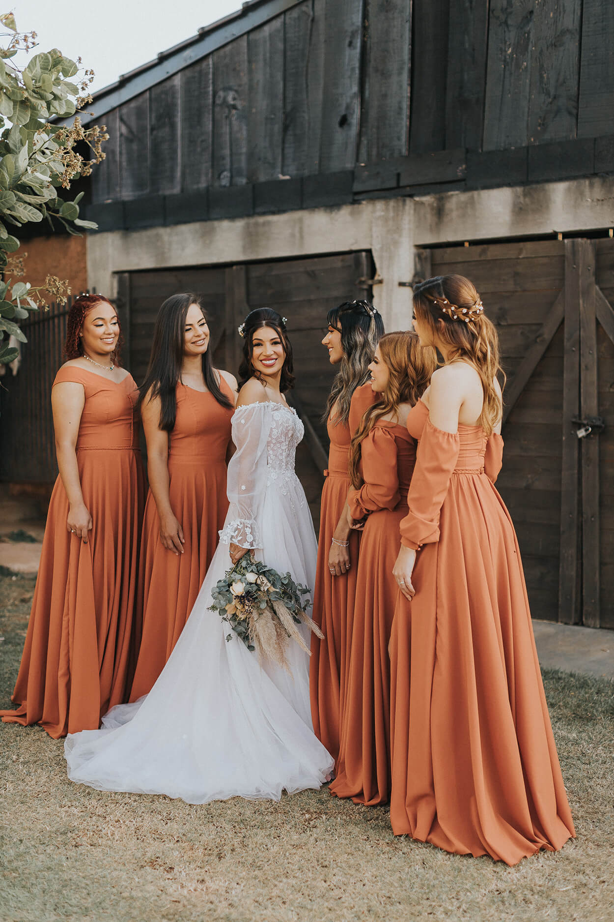 cinco madrinhas com vestidos longos e laranjas de mesmo tom em volta da noiva no jardim