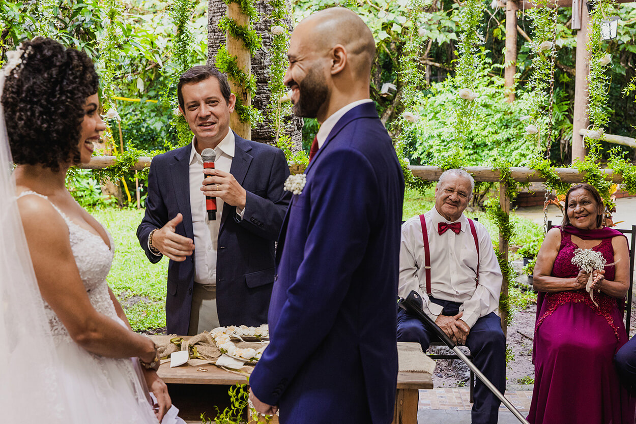 Celebrante de casamento falando no microfone e noivos sorrindo
