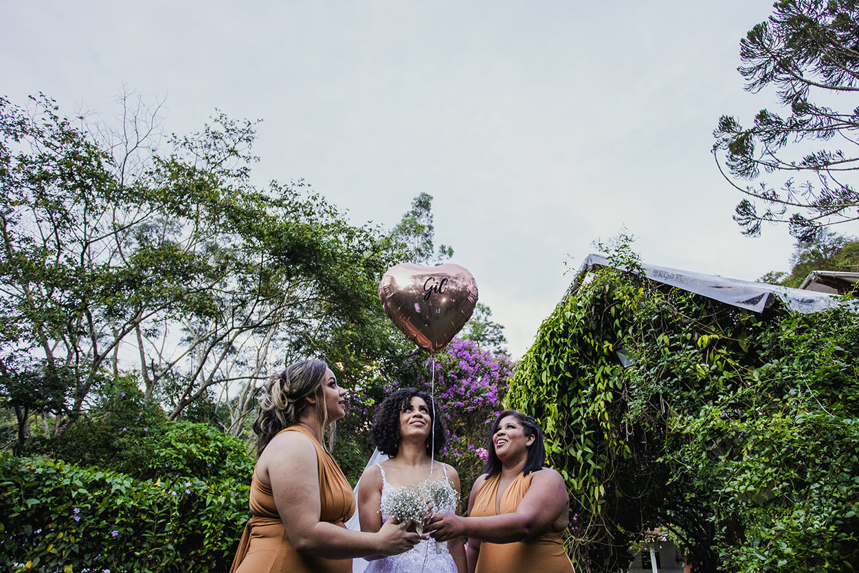 Noiva e madrinhas segurando balão cor de rosa em formato de coração