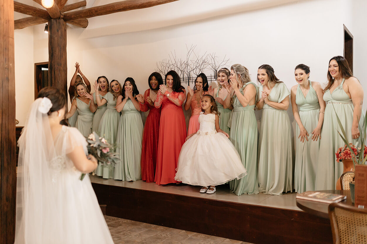 First look da noiva com as mães de vestido laranja e madrinhas com vestido verde