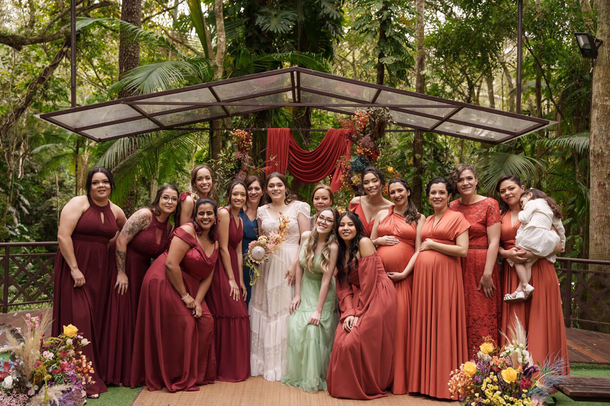 Noiva e madrinhas com vestido longo na cor pêssego e madrinhas com vestido longo na cor veremelha