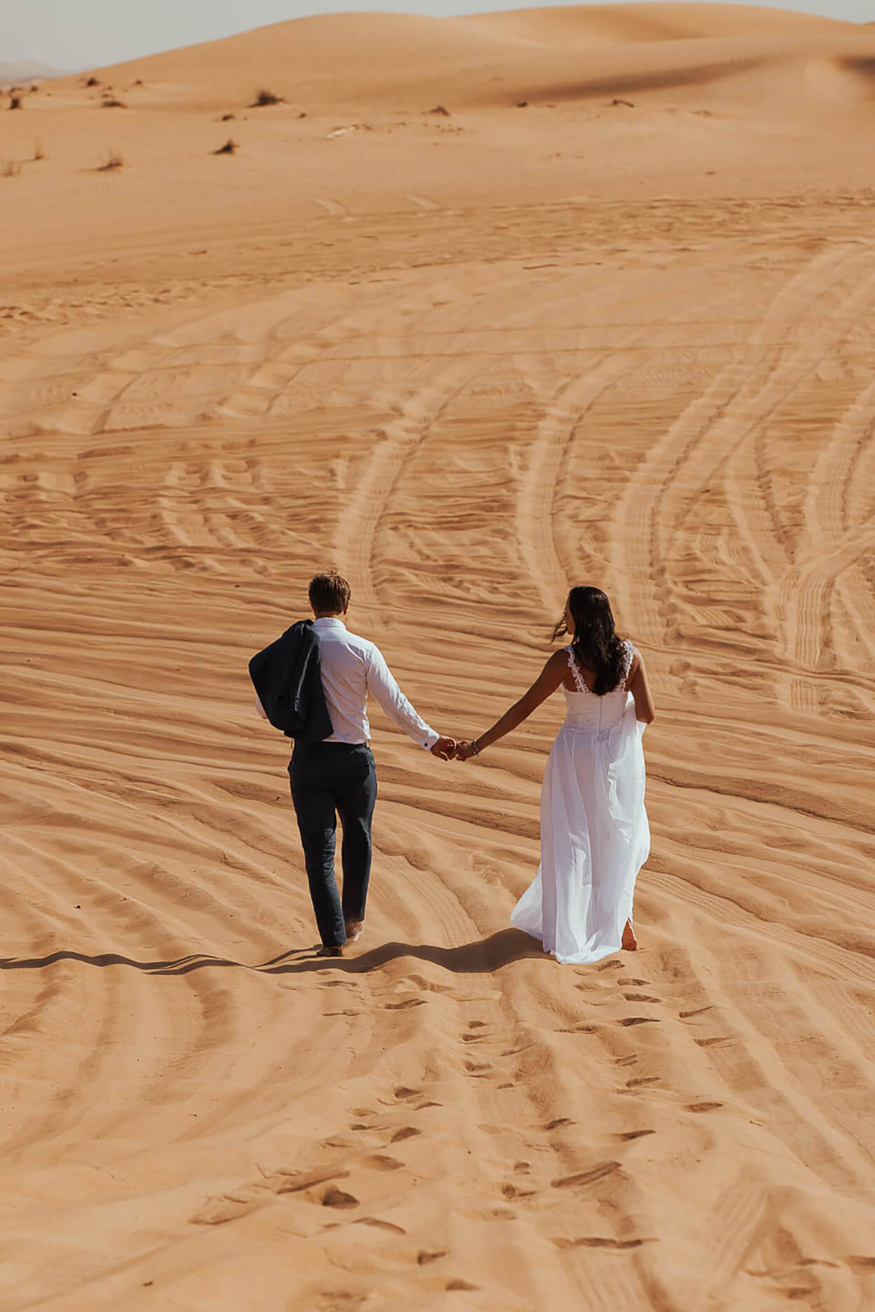 Casal andando de mãos dadas no deserto