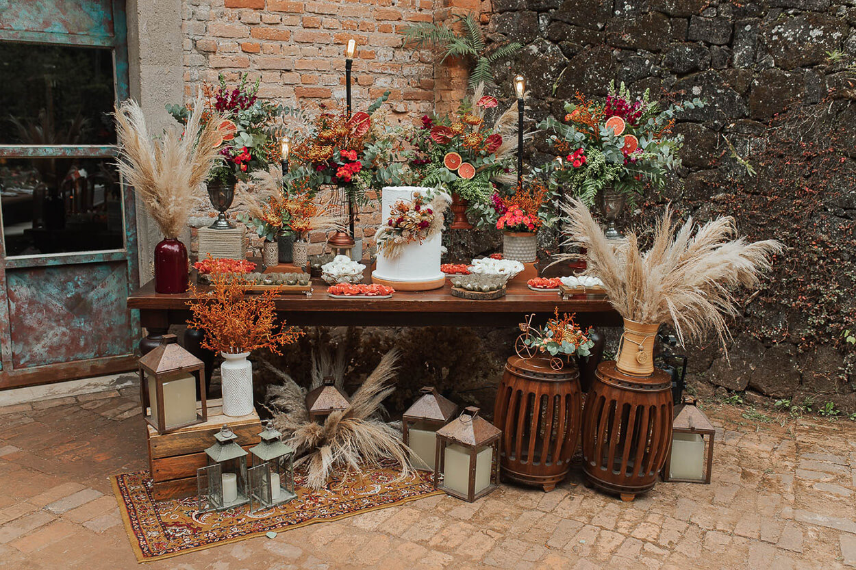 Mesa de madeira com bolo de casamento com capim dos pampas e doces