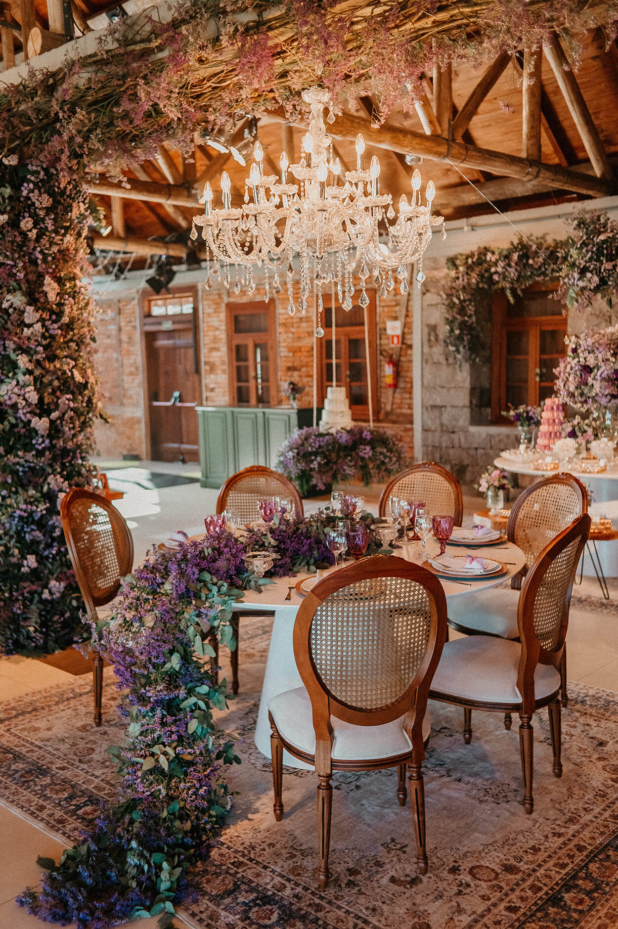 Salão rústico com mesa com arranjo de flores lilás pendentes