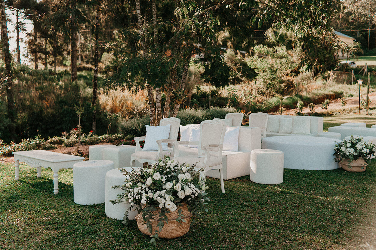 puff, cadeiras brancas e sofás brancos, com e arranjo de flores no campo