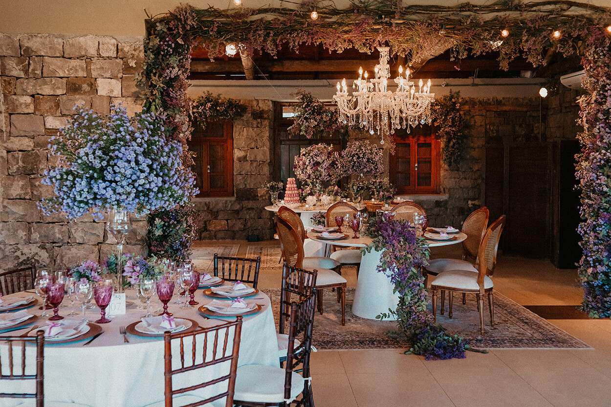 Salão com mesas redondas com flores lilás