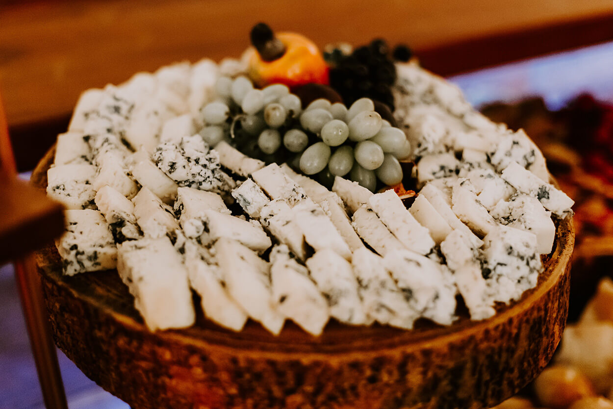 Foto de mesa rústica de madeira com tábua com queijos brancos, uvas e caju