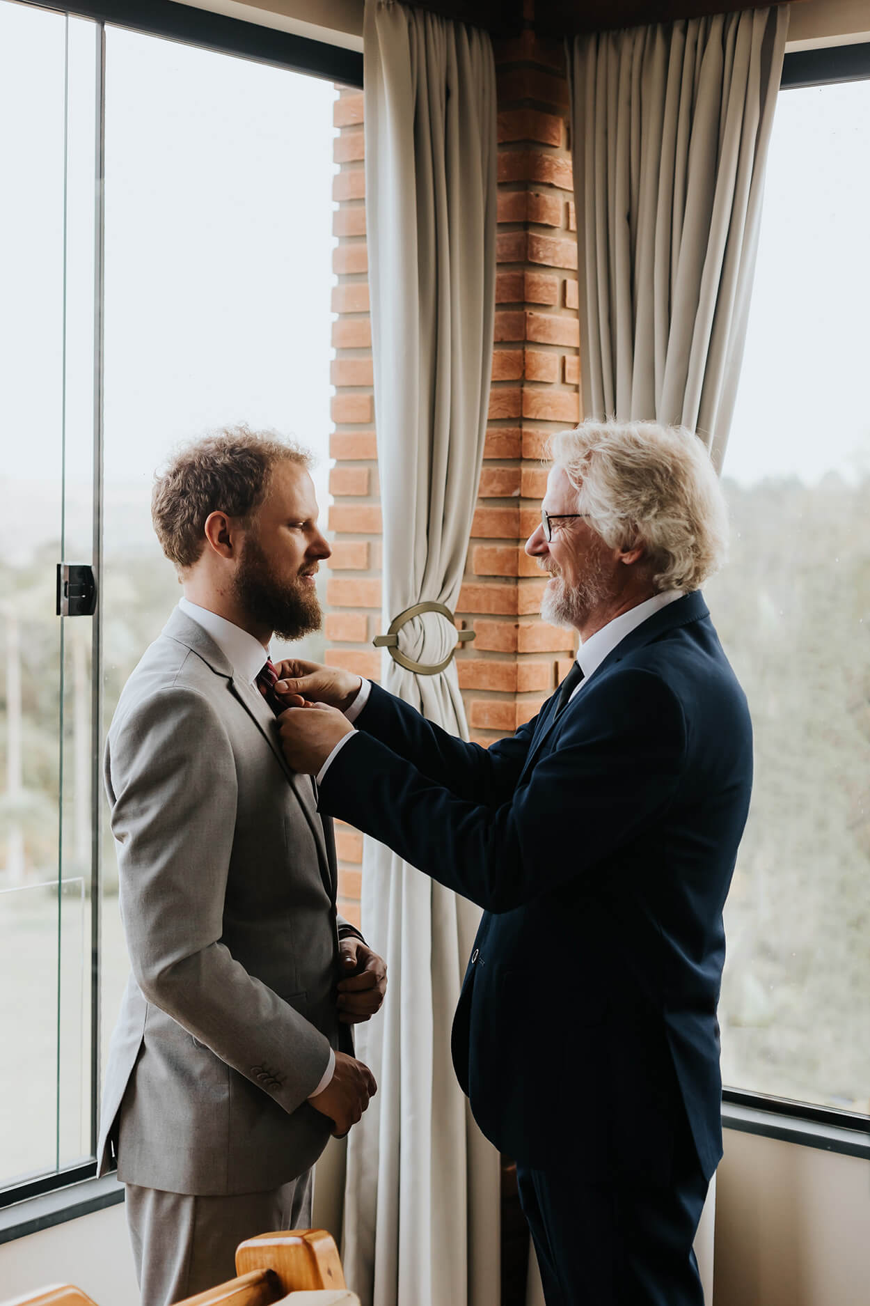 Pai do noivo com terno azul marinho ajustando a gravata do filho