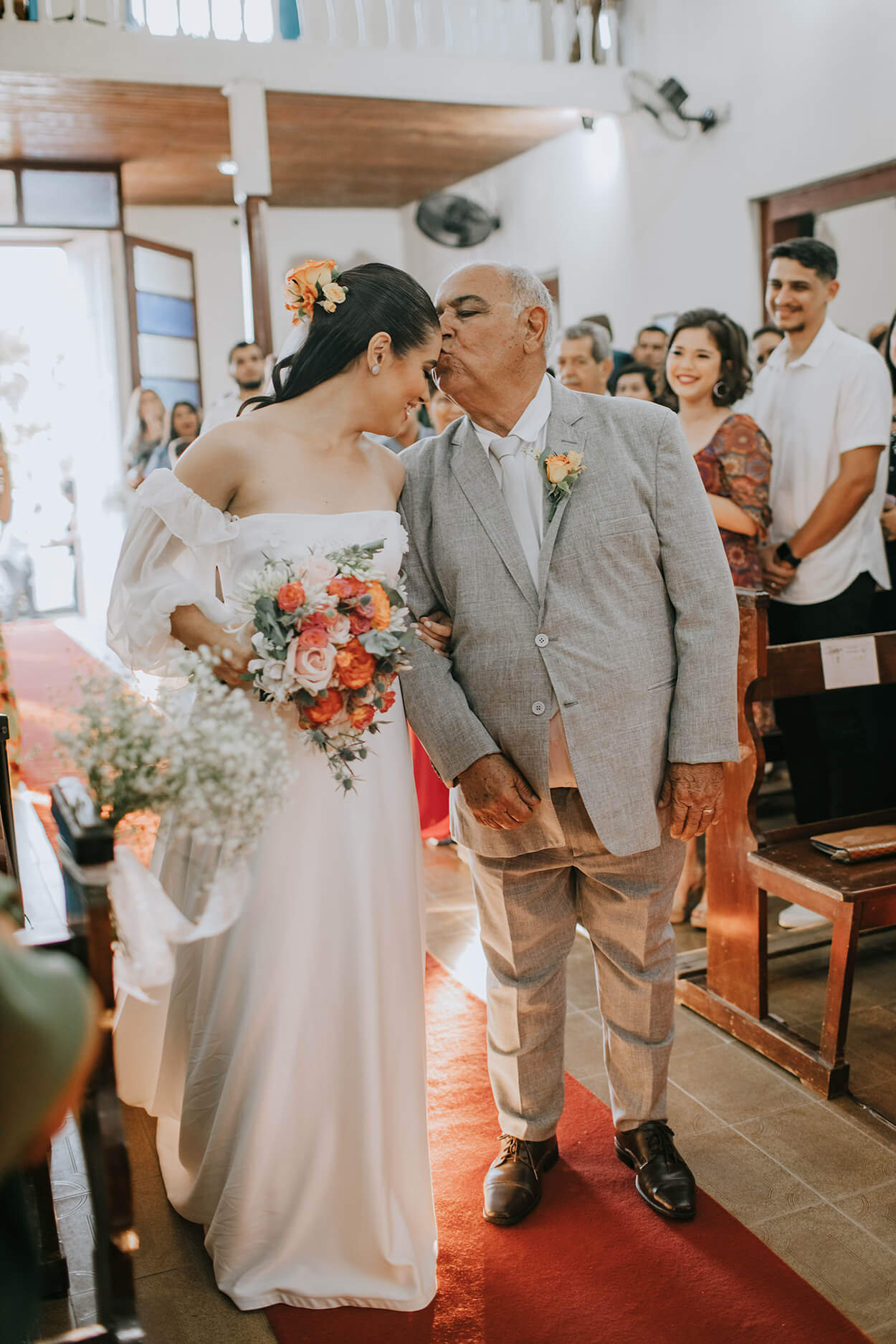Pai da noiva dá um beijo na testa dela na igreja