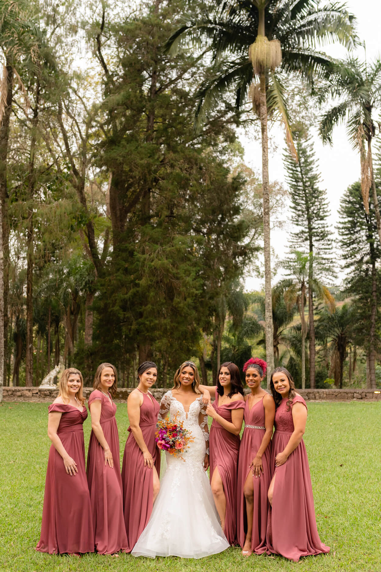 Noiva com seis madrinhas com vestidos longos na cor rosa antigo no campo
