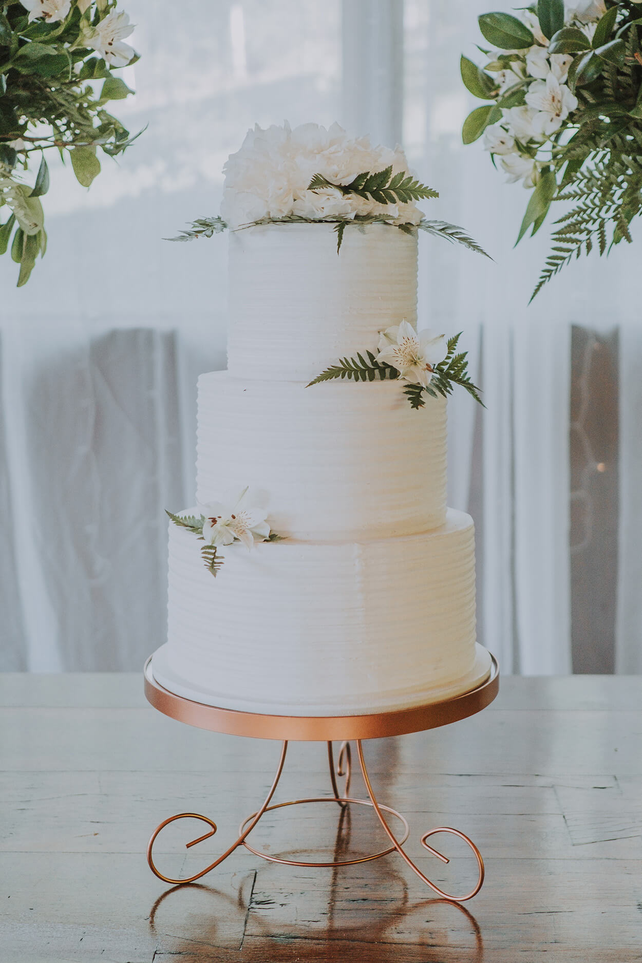 Bolo de casamento branco com topo de bolo com flores brancas e samambaias