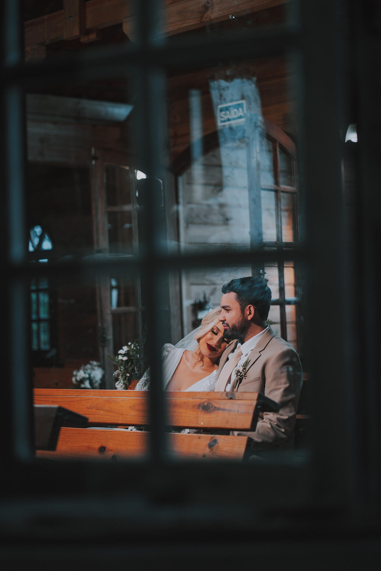 Foto tirada através da janela do casal sentado em banco de madeira