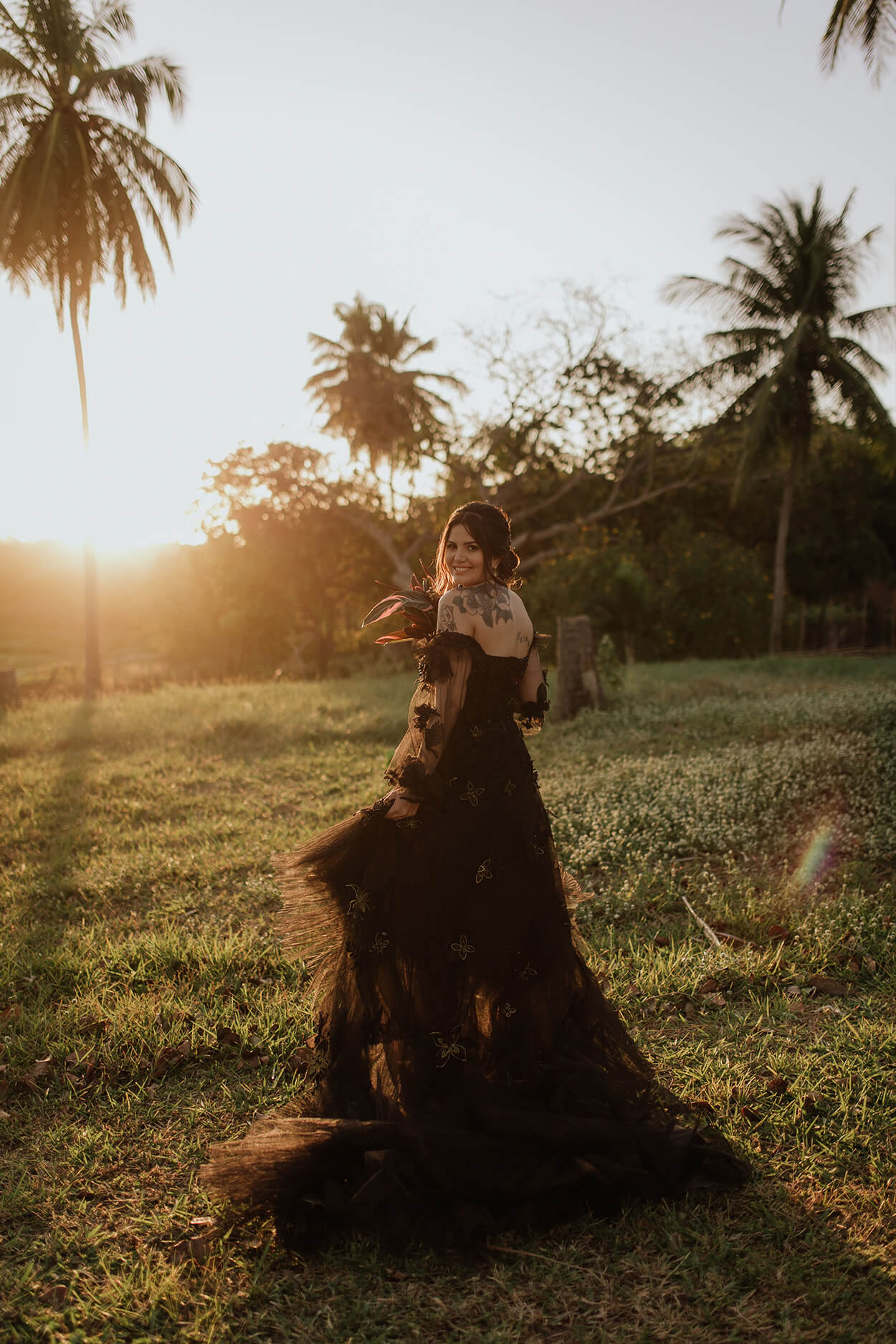 Mulher com vestido de noiva preto de tule ao pôr do sol