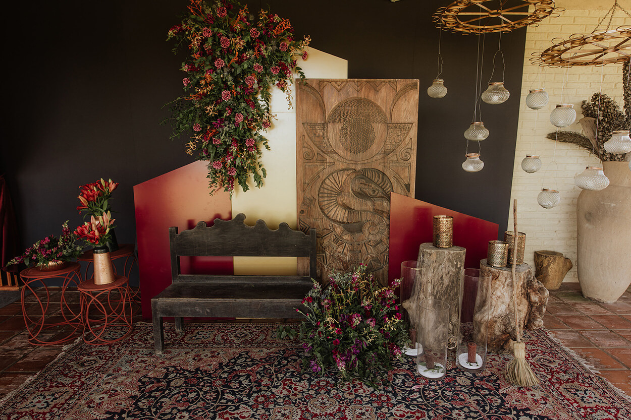 Salão com tapete étnico, banco preto rústico e painéis de madeira com flores