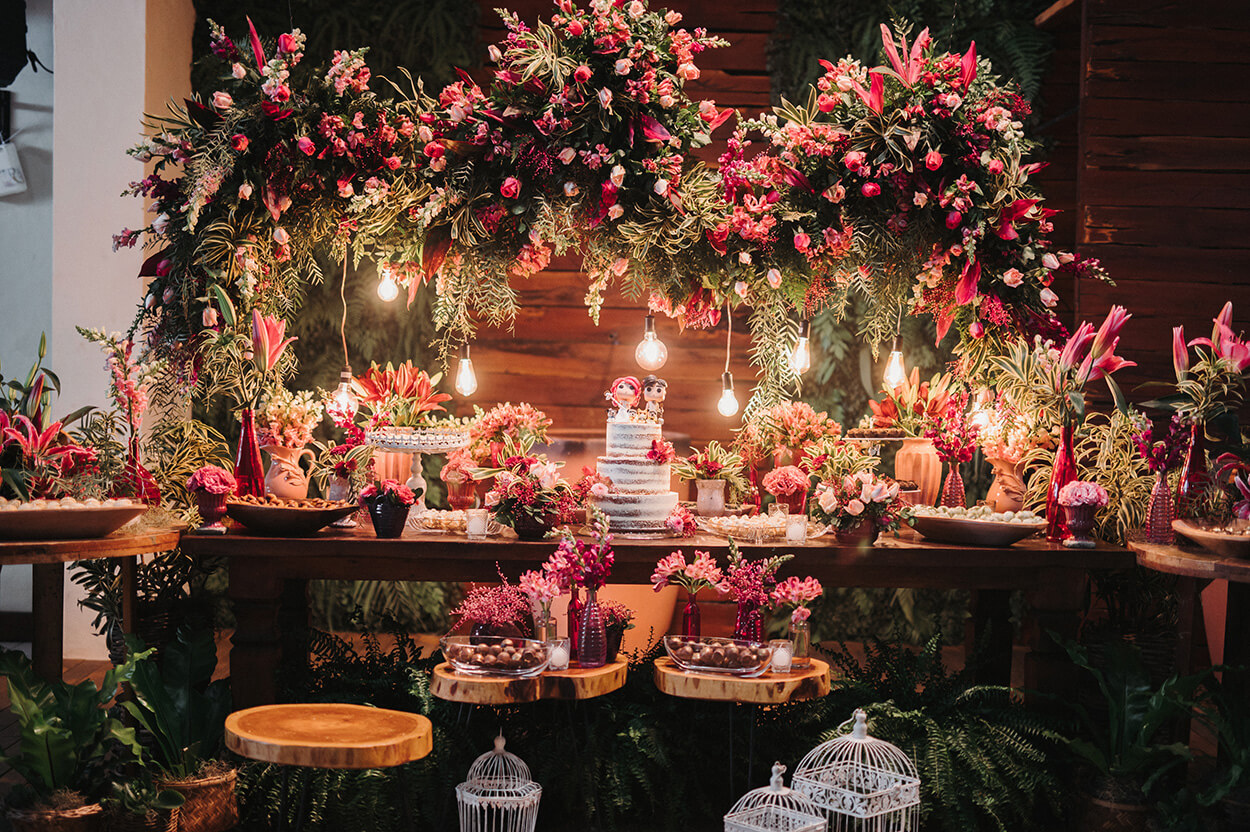 Mesa com bolo de casamento flores rosas e luminárias