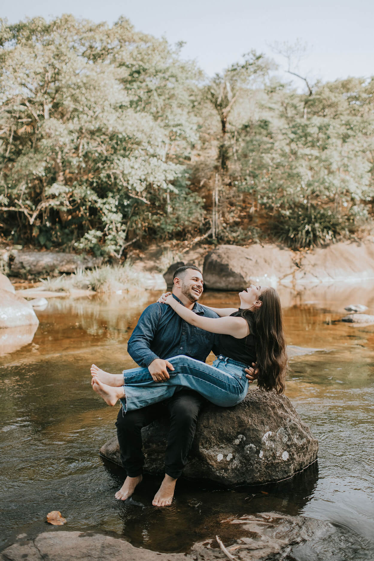Casal se abraçando sobre pedra perto da cachoeira