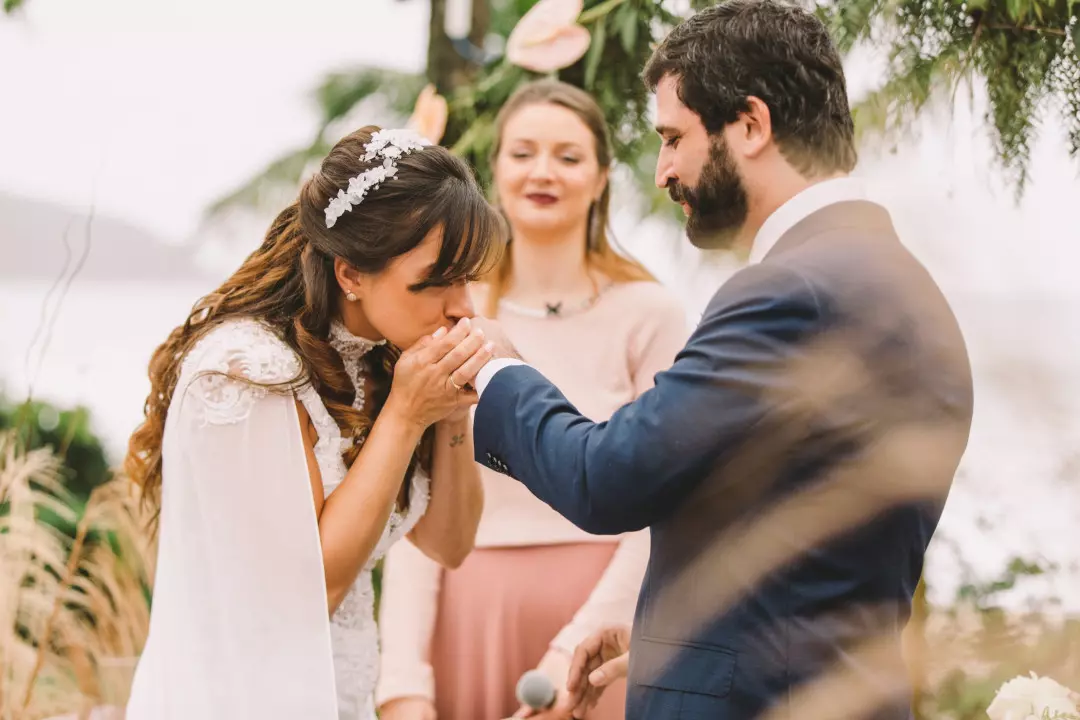 noiva beijando a mão do noivo durante a cerimônia de casamento