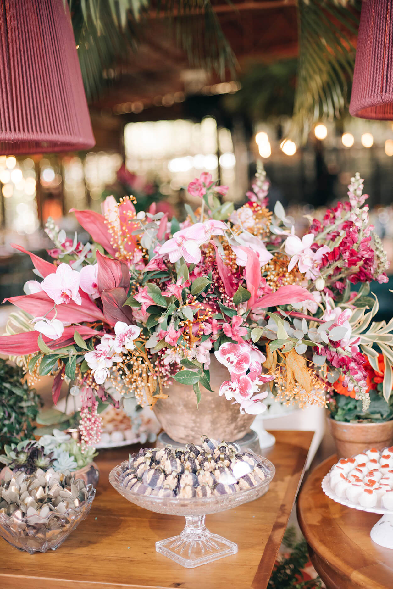 Mesa com vasos cheio de flores rosas e tigelas com doces