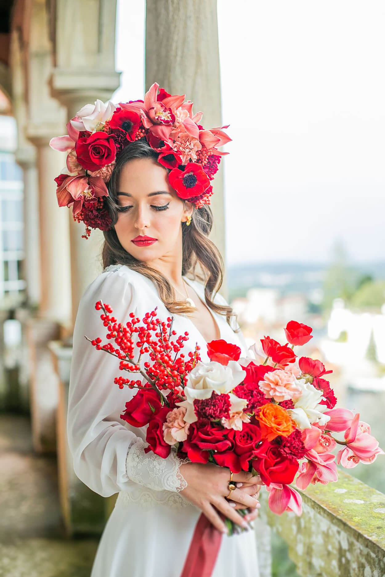 Noiva com coroa de flores veremelhas e buquê com flores brancas, laranajs e vermelhas