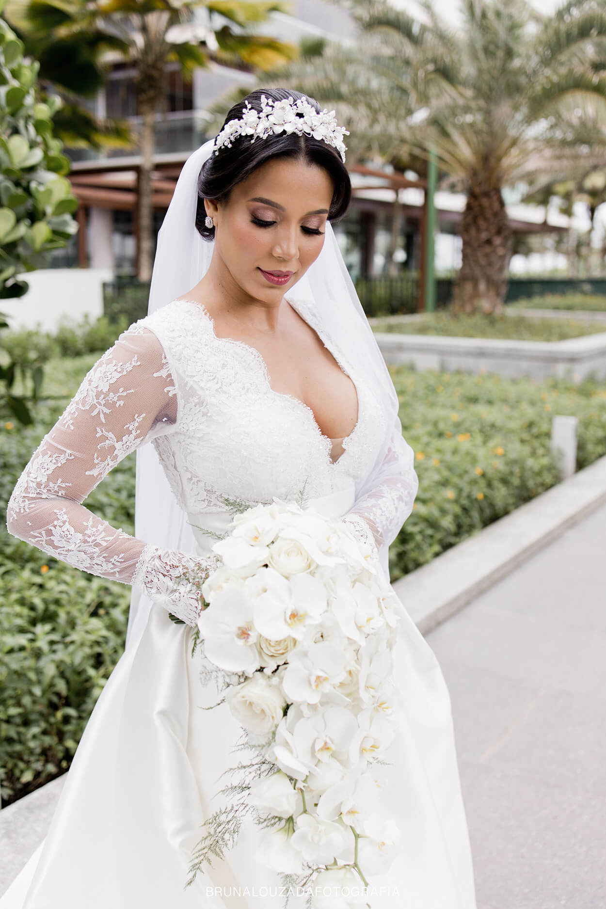Mulher com vetsdiode noiva com mangas compridas segurando buquê com rosas e orquídeas brancas