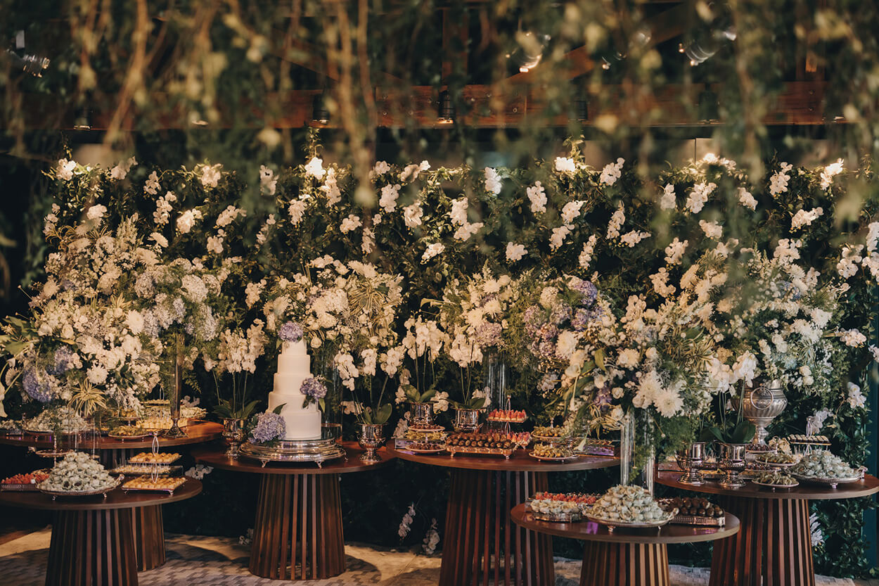 Mesas redondas de madeira com bolo de casamento branco com lilás