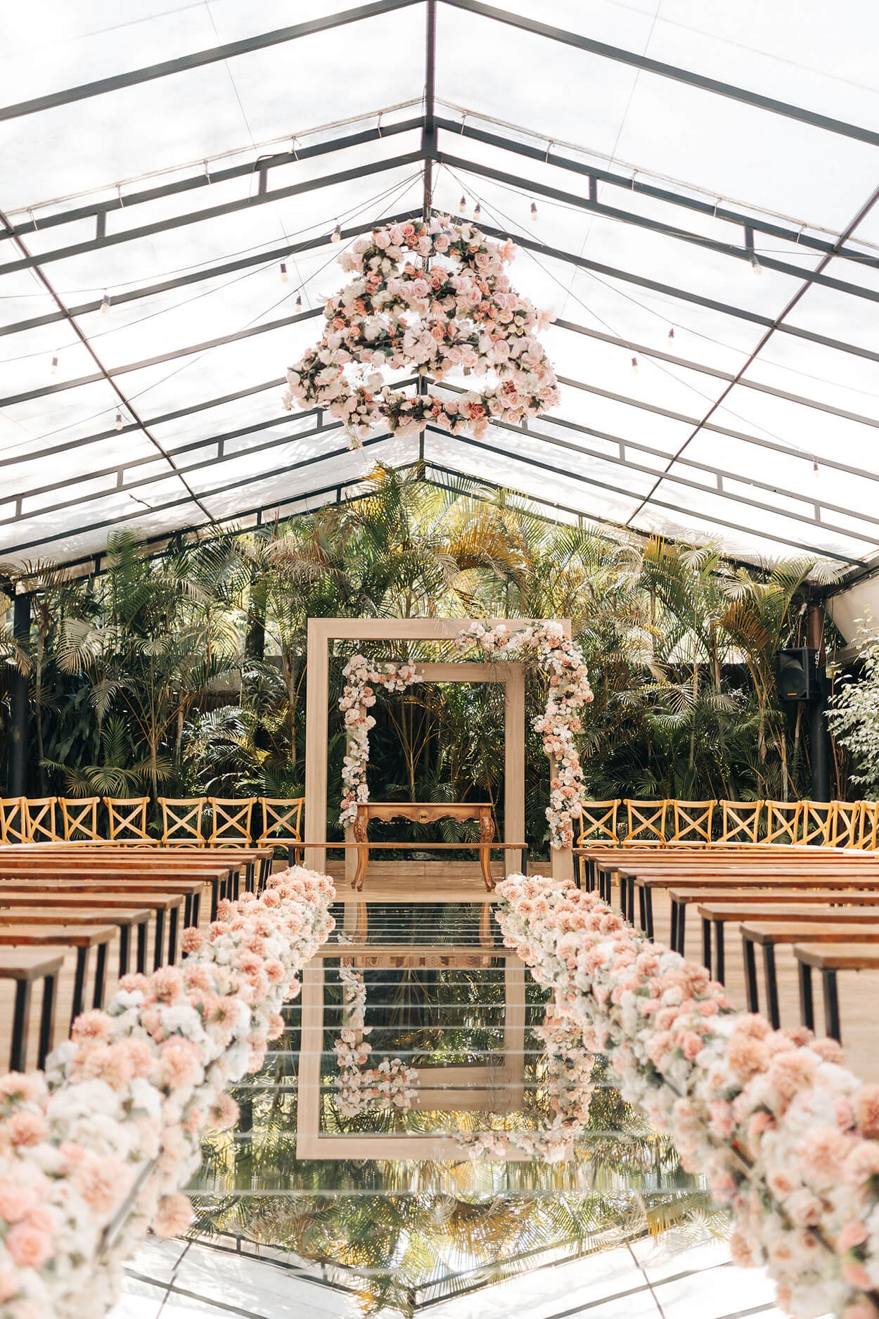 Salão coberto ao ar livre com bancos de madeira flores brancas e rosa e altar de madeira quadrado com flores