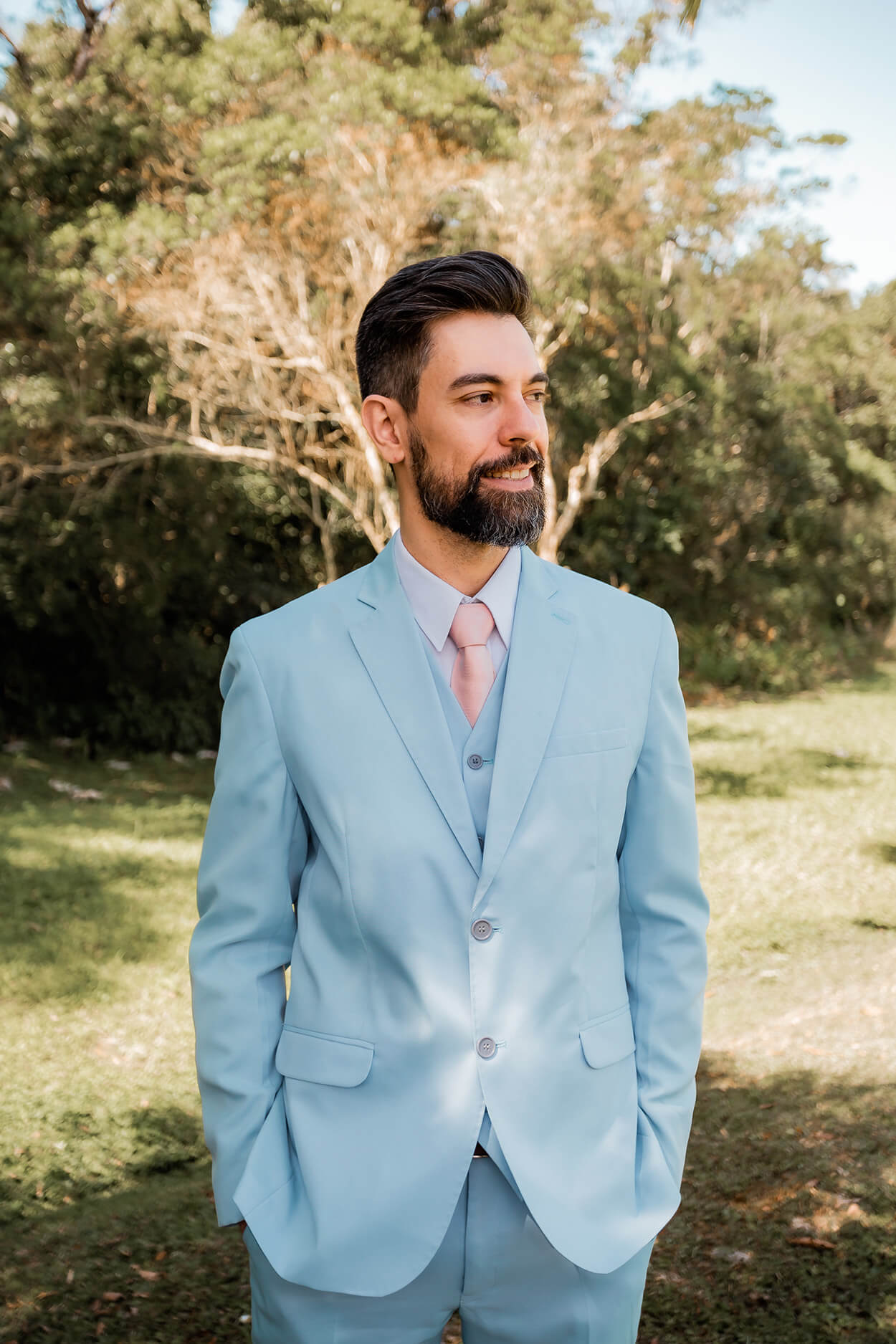 Noivo com terno completo azul e gravata rosa ao ar livre