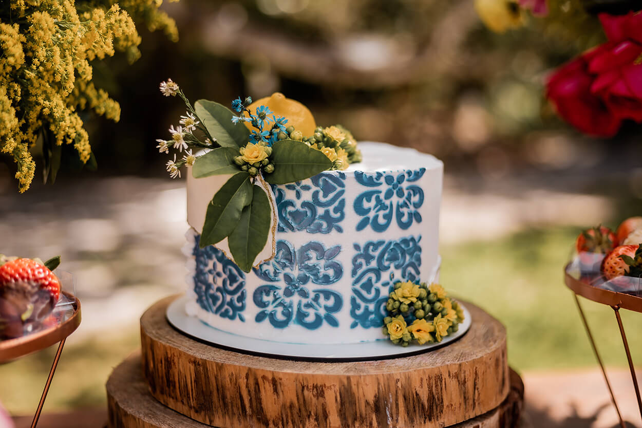 Bolo de casamento branco com arabescos azuis e flores amarelas