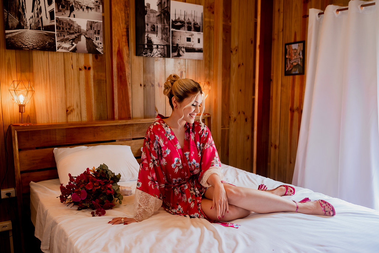 Noiva com robe rosa florido deitada na cama