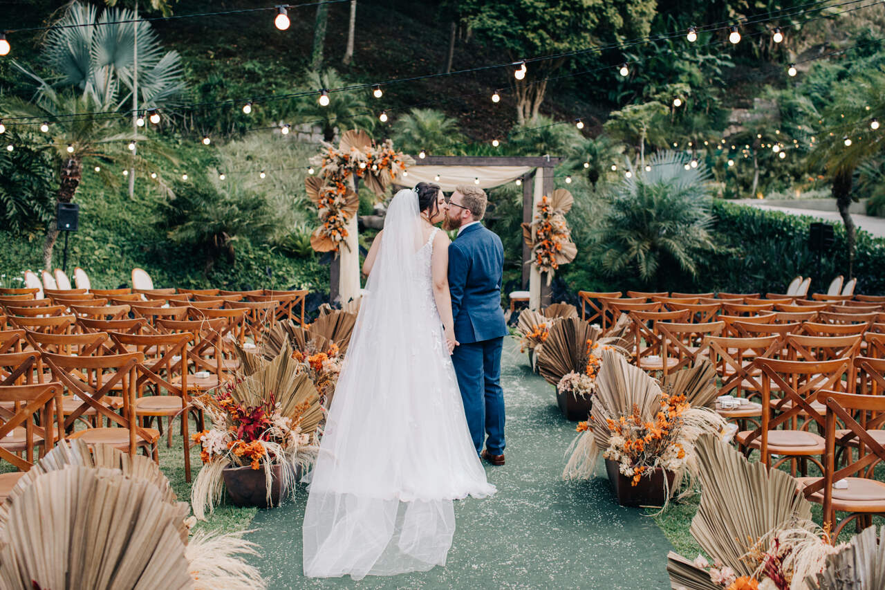 casal de noivos se beijando em área de cerimônia ao ar livre na casa do alto eventos