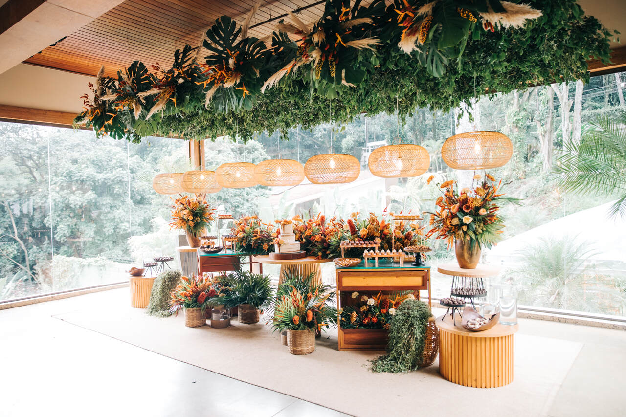 mesa de bolo e doces de casamento com decoração verde, laranja e madeira em salão de festas da casa do alto eventos