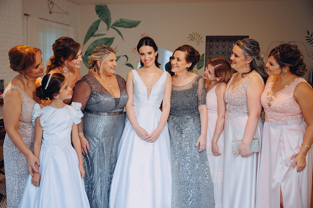 Noiva e mulheres com vestidos rosa e prata ao lado dela