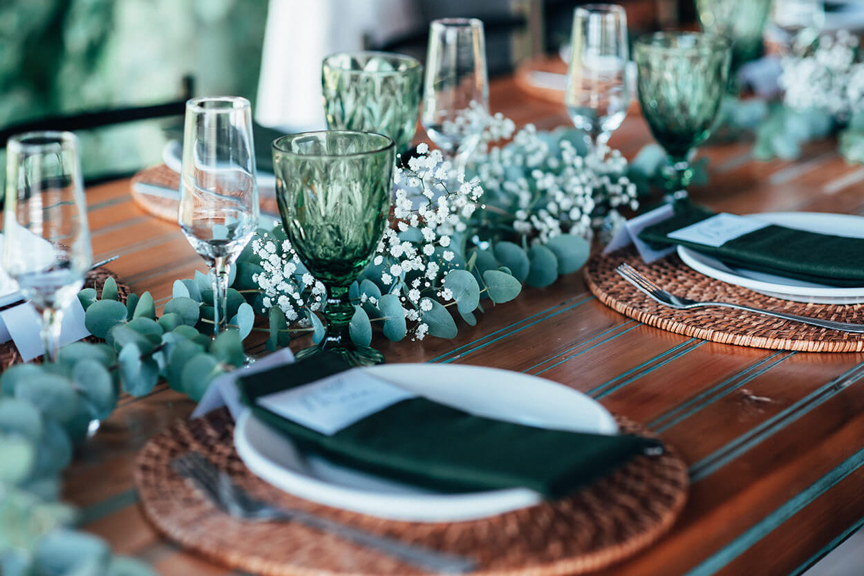 Mesa posta com taças verdes e flores brancas