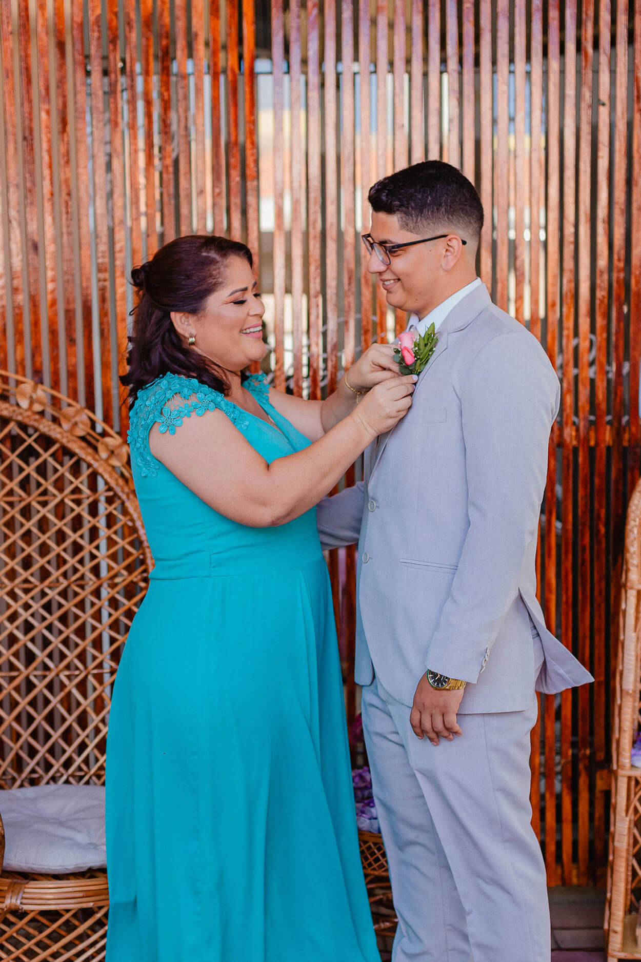Mãe do noivo com vestido azul turquesa ajustando o terno do noivo