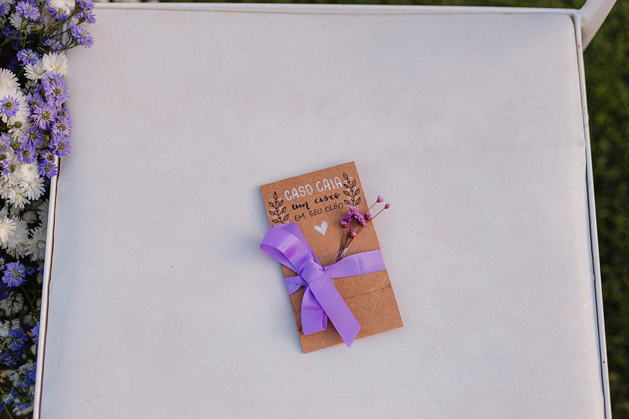 Pequeno marcador de assento na cor craft com flor e laço lilás na cadeira