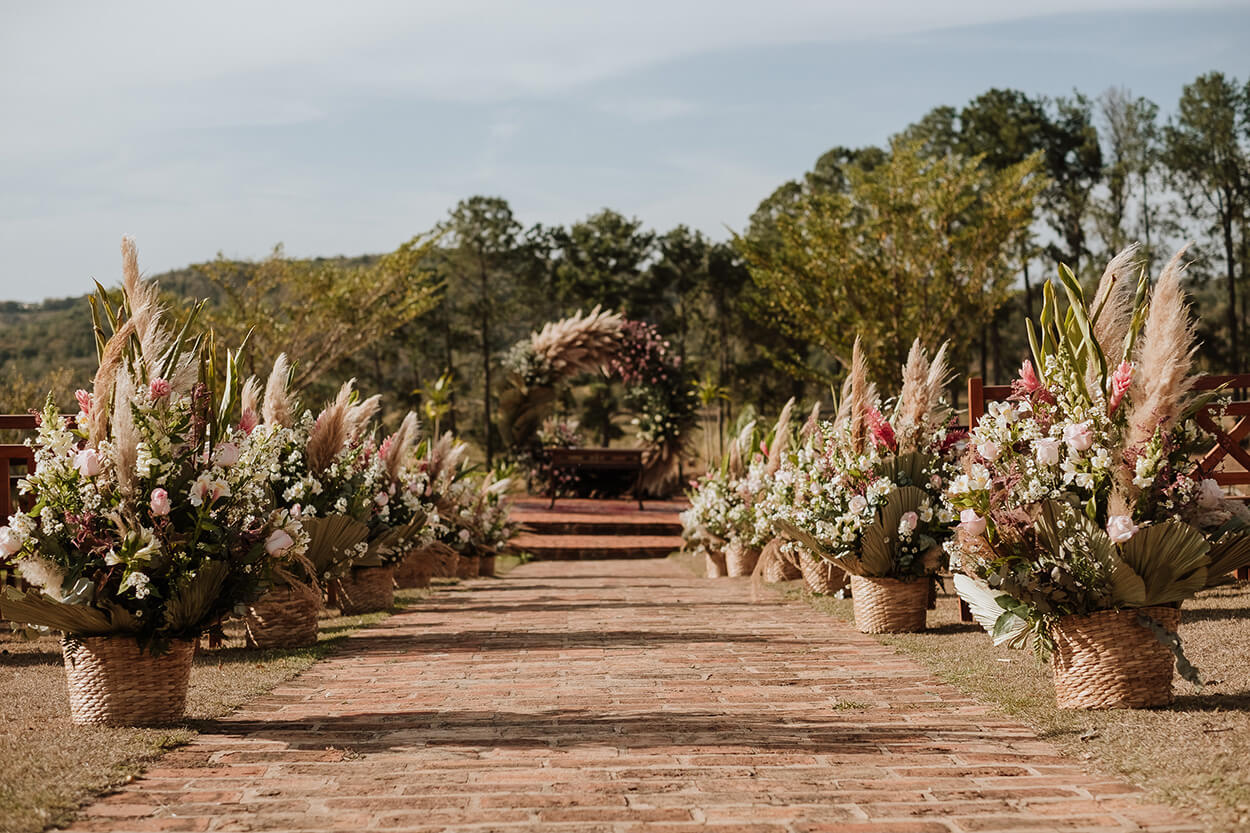 Caminho da noiva até o altar com vasos com capim dos pampas rosas e folhas secas