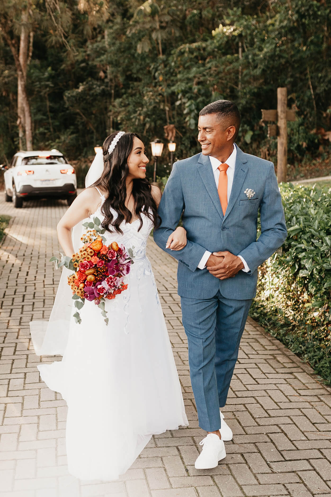 Entrada da noiva com seu pai vestindo terno azul com gravata laranja clara