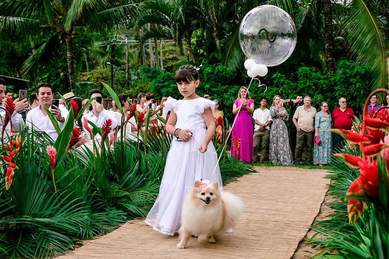 Dmainha com vestido branco segurando balão transparente e levando cachorro