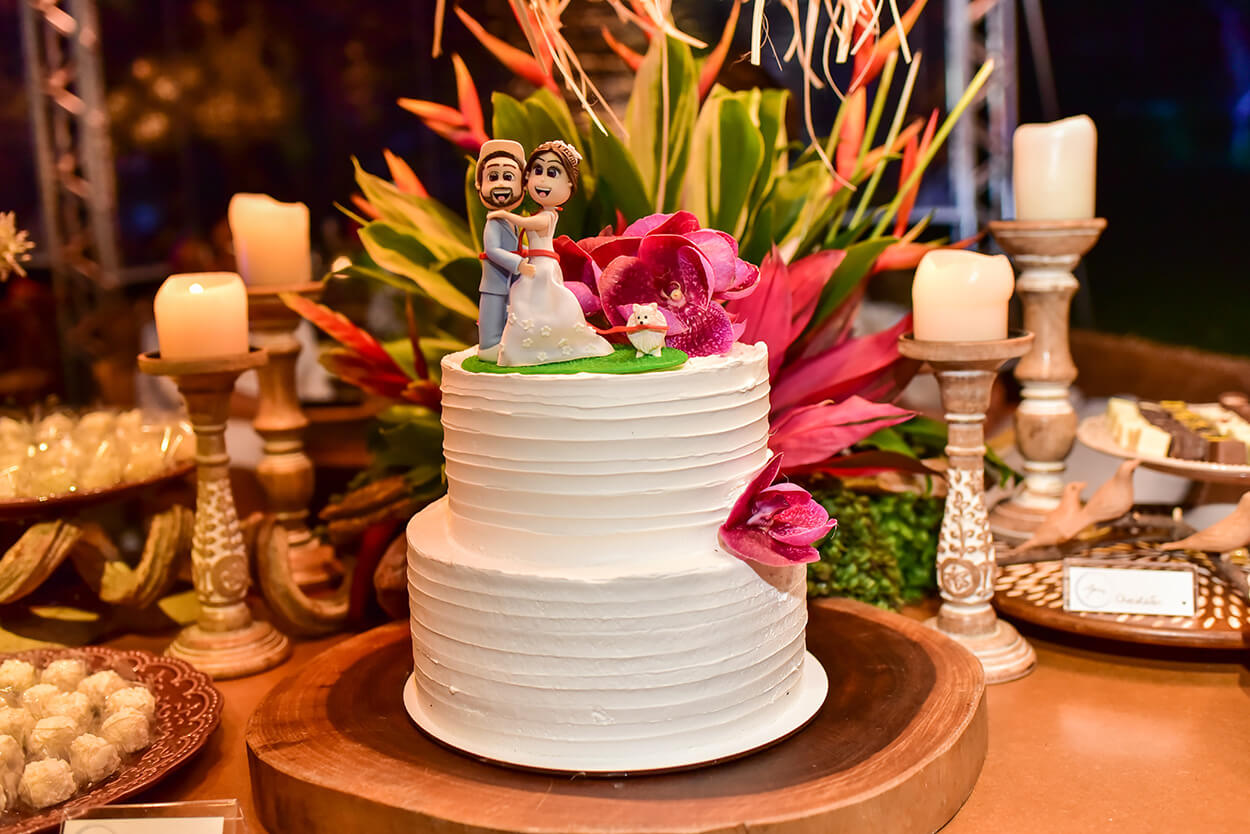 Bolo de casamento branco espatulado com flores rosas e bonequinhos dos noivos