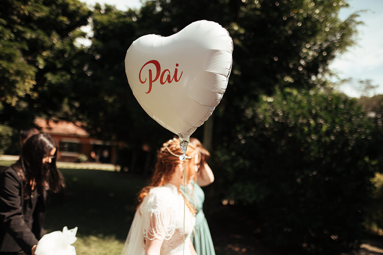 Noiva segurando balão branco em forma de coração escrito pai