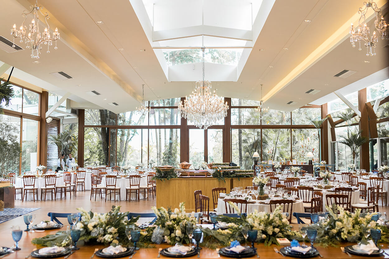 Salão de festas com vista para natureza com mesas com toalhas brancas