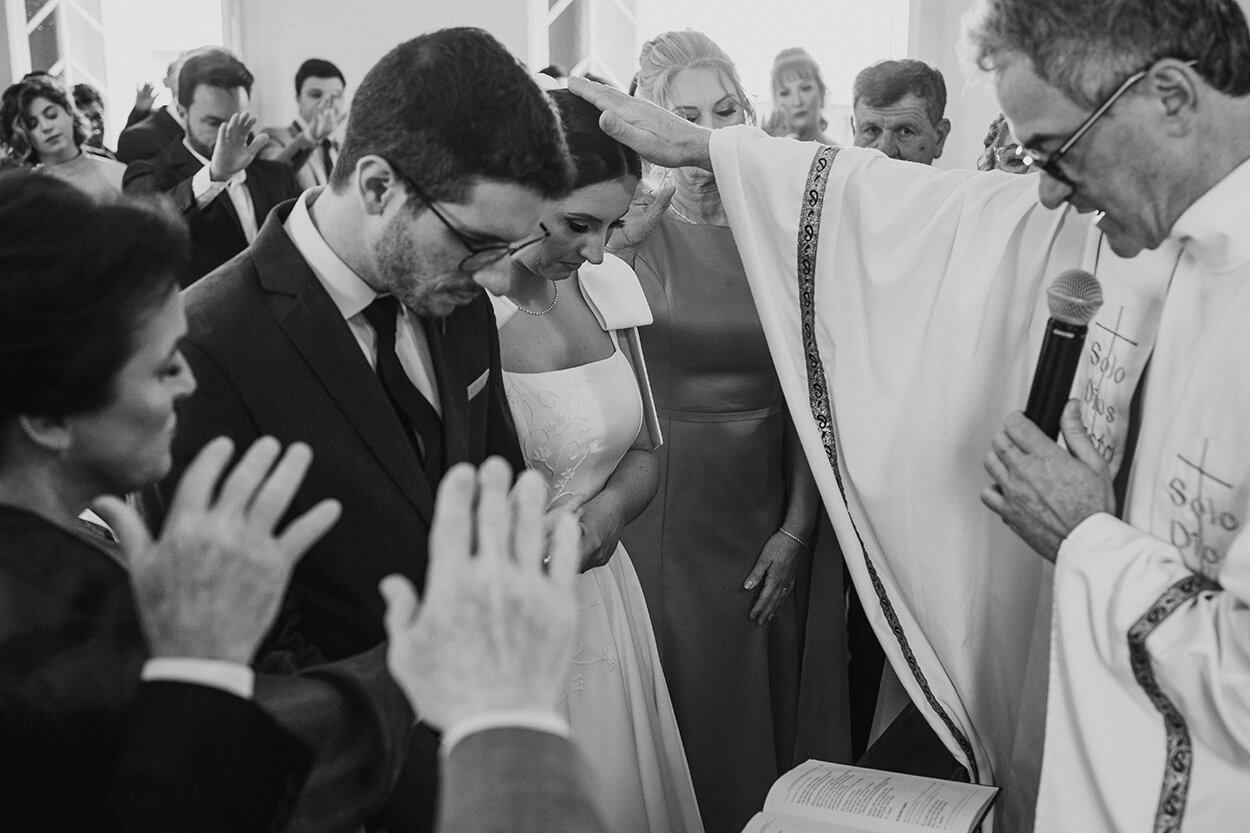 Padre orando para os noivos no altar