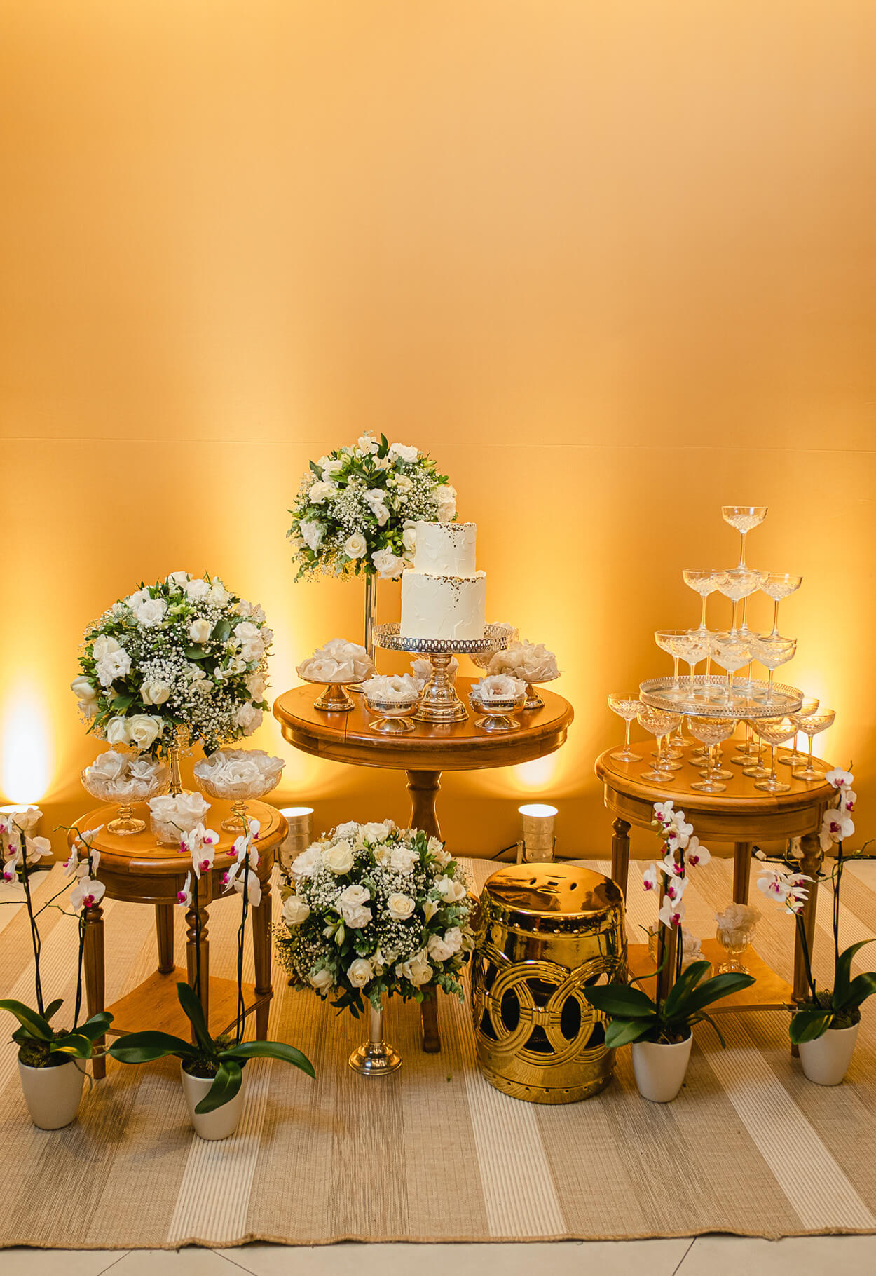 Mesas redondads com bolo de casamento, tlas e arranjos ocm flores brancas