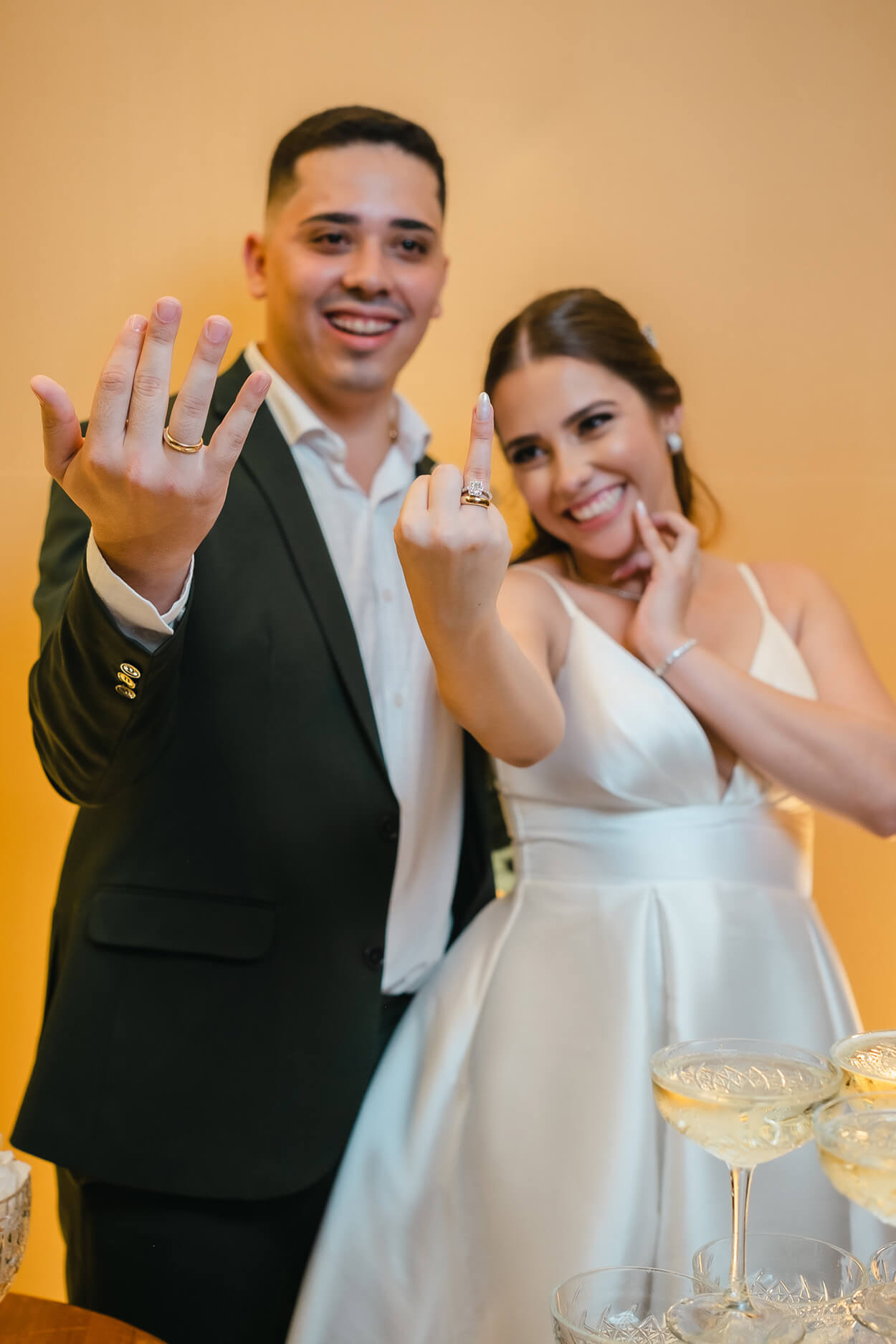 Noivos sorrindo e mostrando as mãos com a aliança de noivado