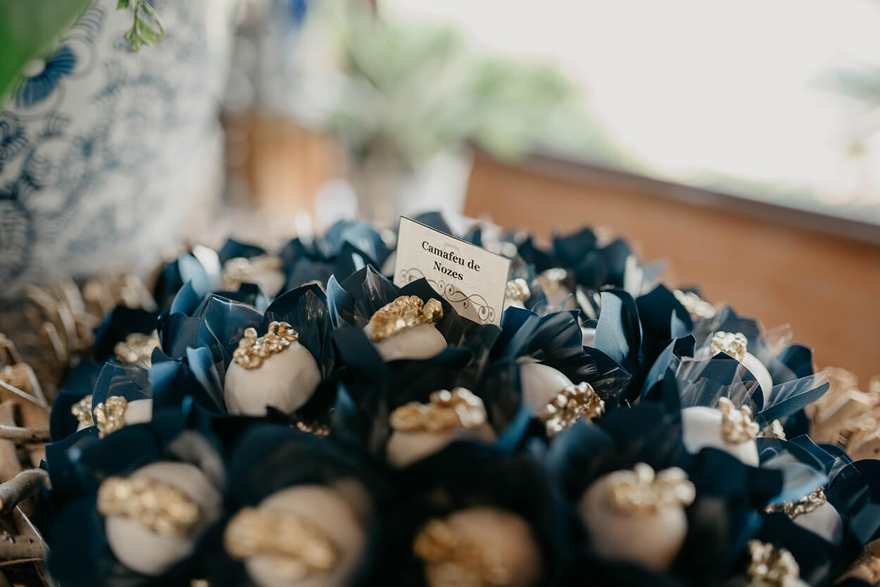Bandeja com doces finos de casamento com nozes douradas em forminhas azuis marinho