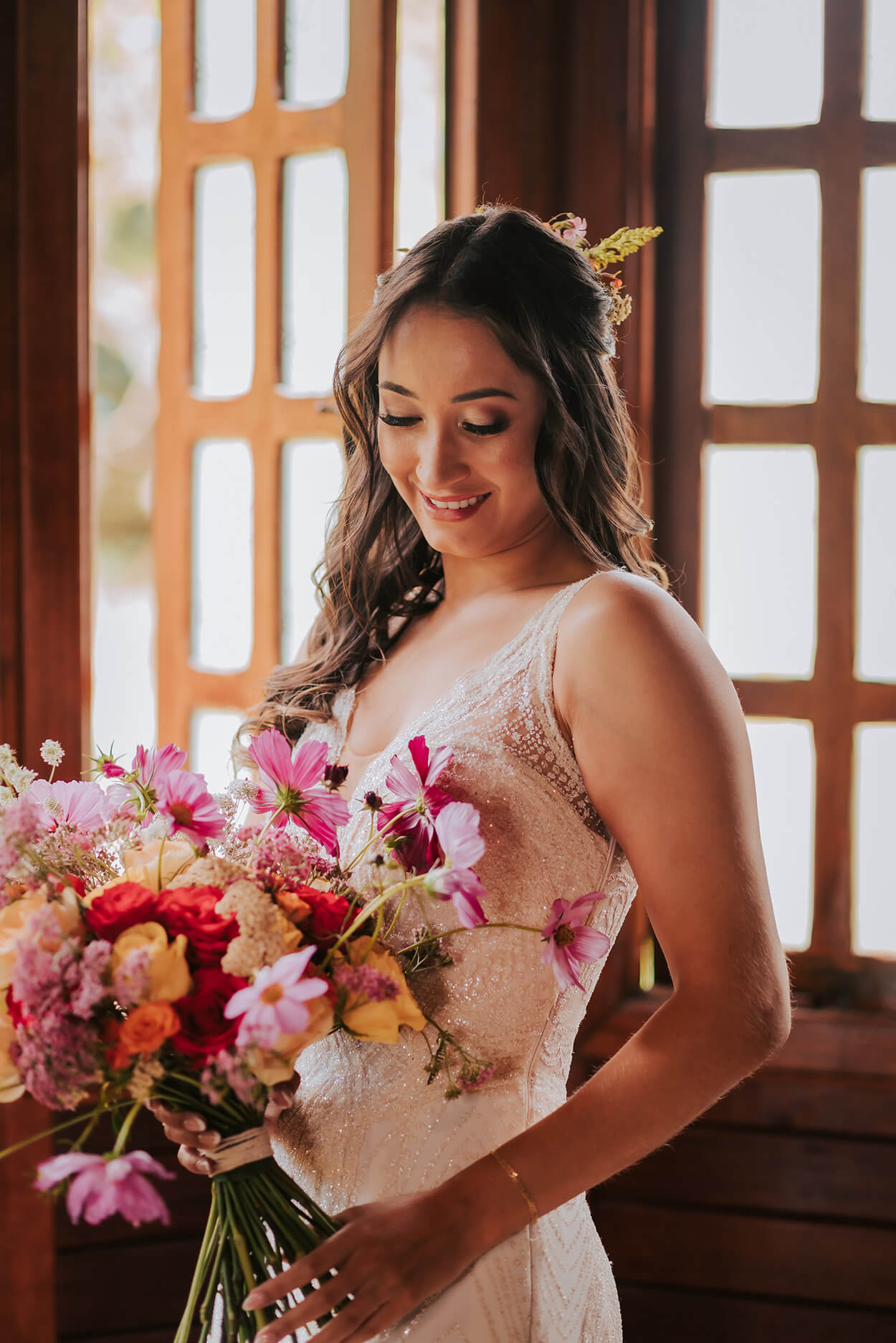 Noiva com vestido rendado segurando buquê com flores rosas