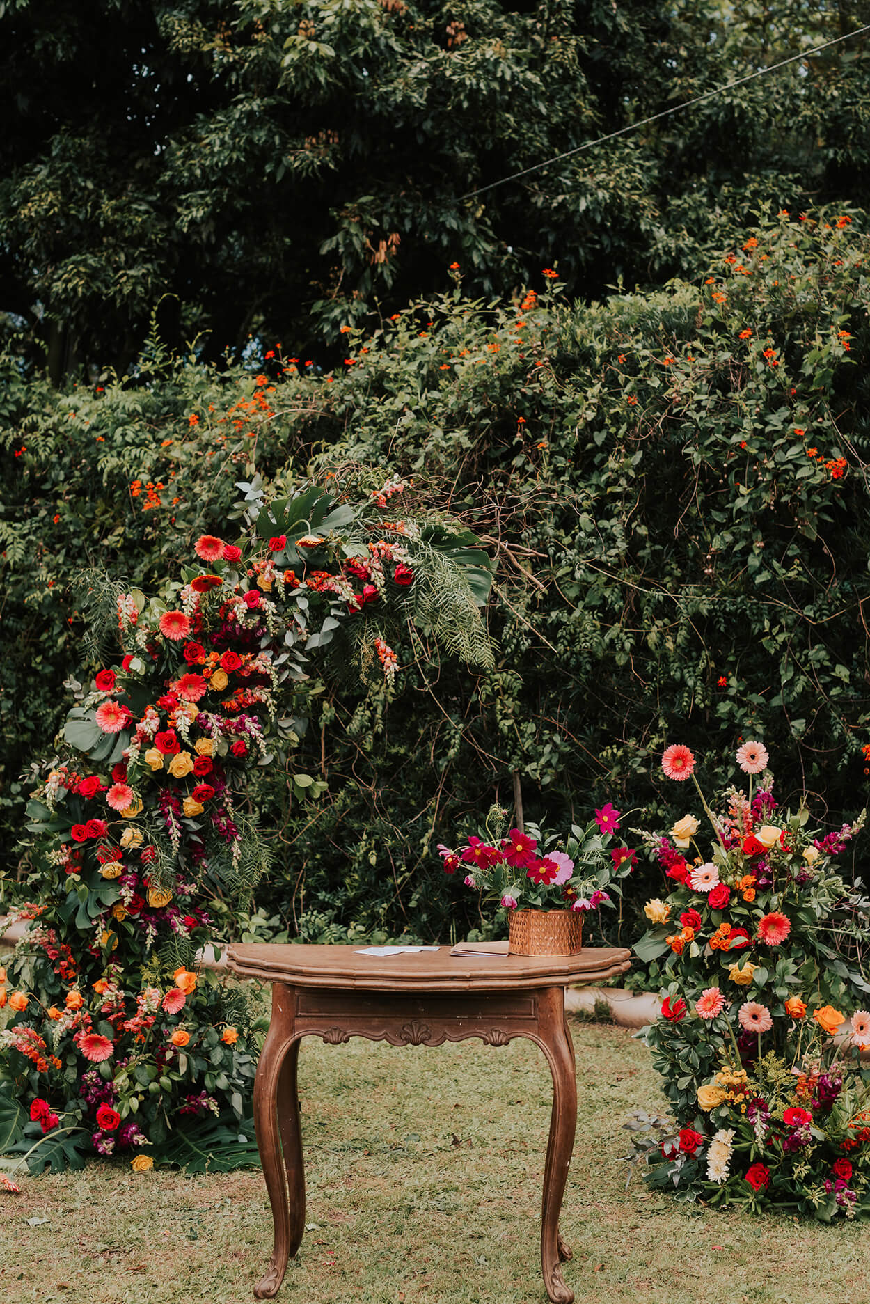 Altar com arco de flores vermelhas, amarelas e rosas
