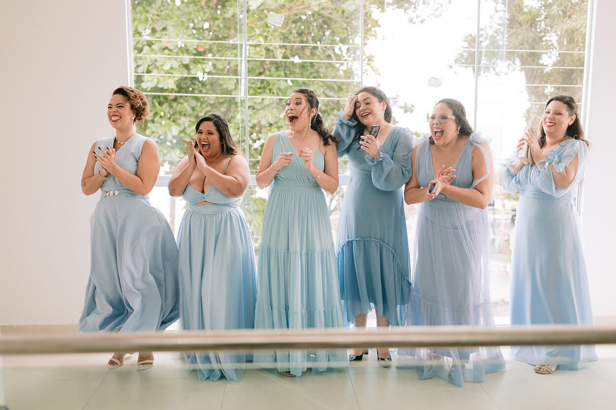 seis mulheres com vestidos na cor azul serenity animadas ao ver a noiva